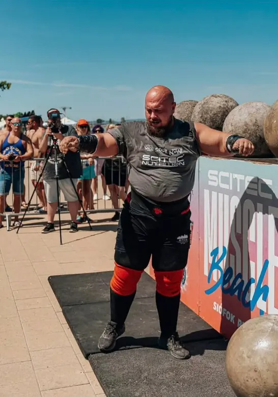 Vlad leaning on atlas stones at a strongman competition, focused before his lift